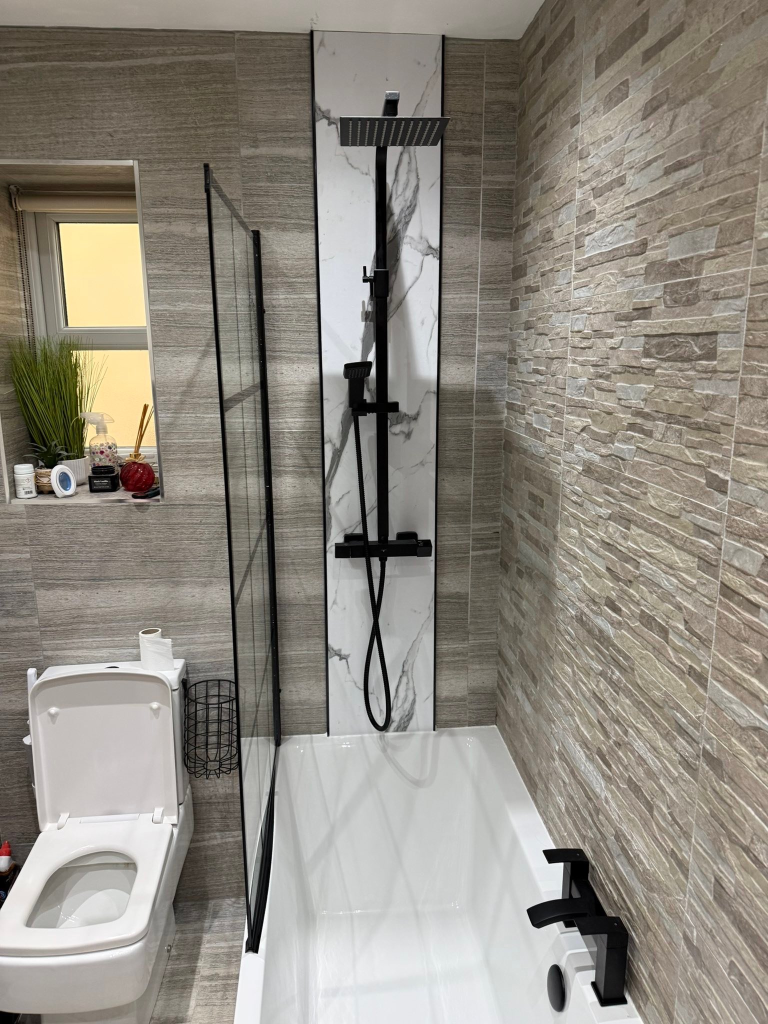 Customer bathroom installation — modern shower bath with black brassware